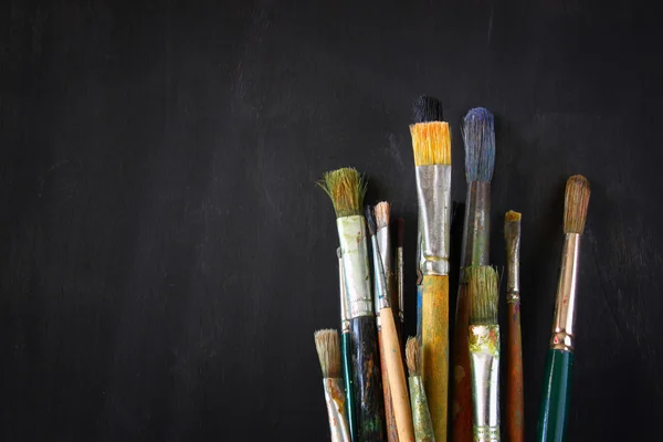 Paint brushes over blackboard background — Stock Photo, Image