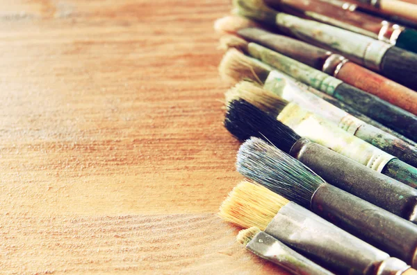 Top view of set of used paint brushes over wooden table — Stock Photo, Image