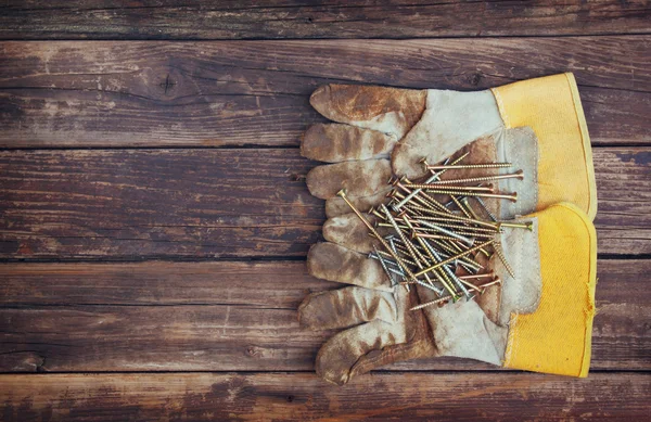 Top view of worn work gloves and assorted work tools over wooden background — Stock Photo, Image