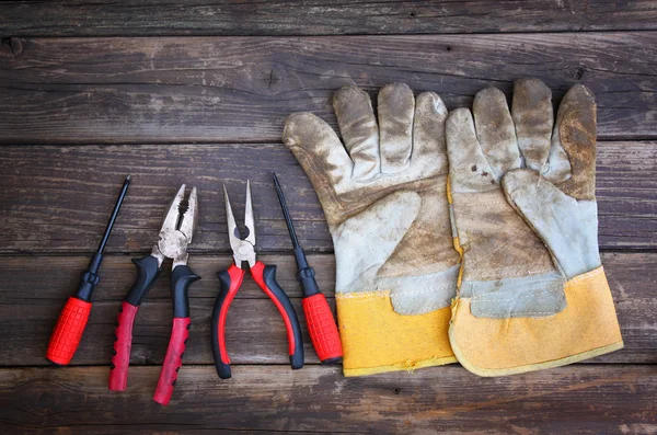 Top view of worn work gloves and assorted work tools over wooden background — Stock Photo, Image