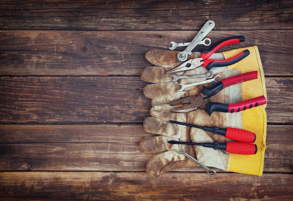Top view of worn work gloves and assorted work tools over wooden background — Stock Photo, Image