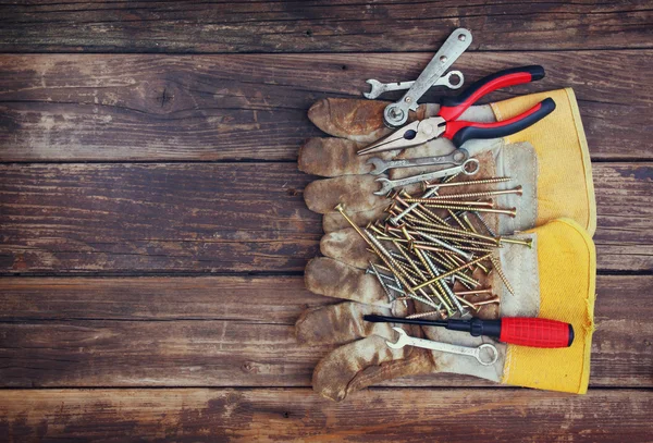 Top view of worn work gloves and assorted work tools over wooden background — Stock Photo, Image