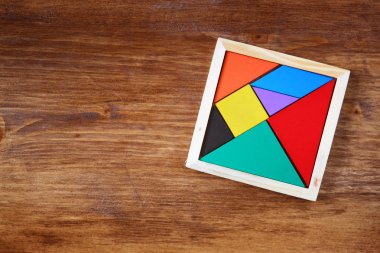 Kayıp bir parça kare tangram içinde üstten görünüm Bulmaca, ahşap masa üzerinde.
