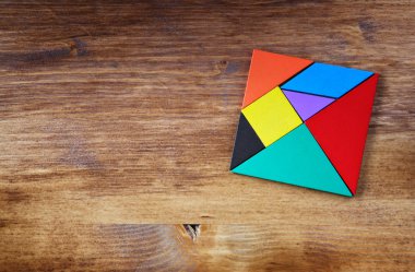Kayıp bir parça kare tangram içinde üstten görünüm Bulmaca, ahşap masa üzerinde.