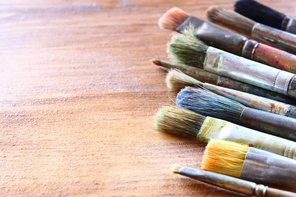Верхний вид набора использованных кистей краски над деревянным столом — стоковое фото