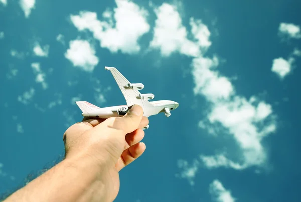 Photo rapprochée de la main de la femme tenant un avion jouet contre le ciel bleu avec des nuages. image filtrée — Photo