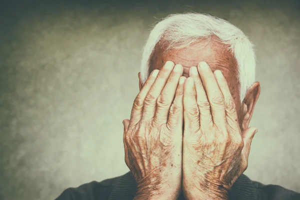 Portret van senior man die betrekking hebben op zijn gezicht met zijn handen. Retro gefilterde afbeelding — Stockfoto