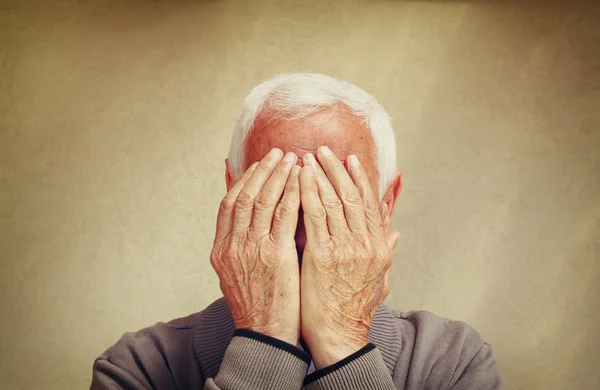 Portret starszego człowieka ukrywszy twarz rękami. retro filtrowanego obrazu — Zdjęcie stockowe