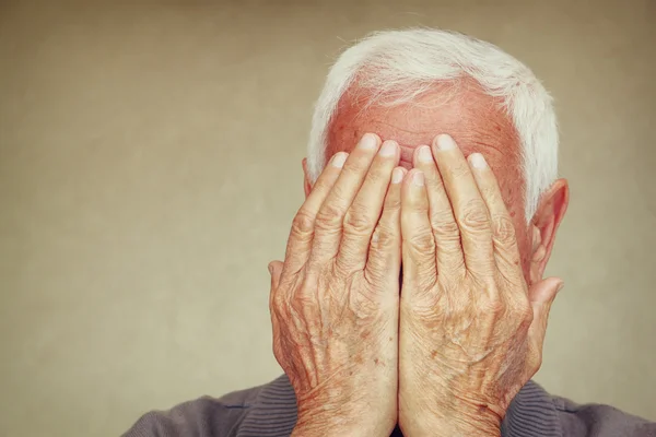 Retrato de un hombre mayor cubriéndose la cara con las manos. imagen filtrada retro — Foto de Stock