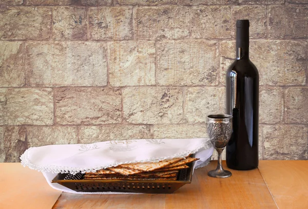Pascha achtergrond. wijn en matzoh (joodse Pesach brood) op houten tafel en wand textuur van Jeruzalem steen — Stockfoto