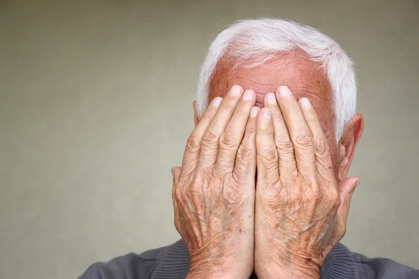 Porträt eines älteren Mannes, der sein Gesicht mit den Händen bedeckt — Stockfoto