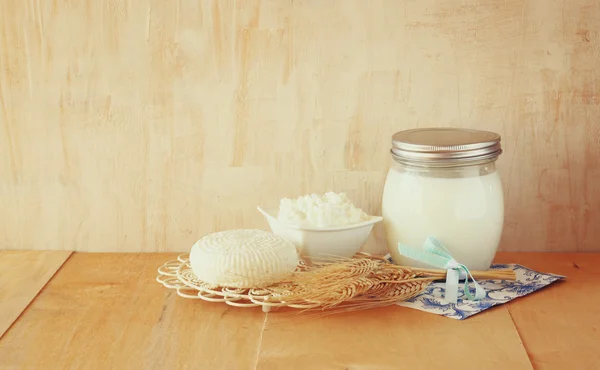 Gresk ost, hytter og melk på trebord med teksturert bakgrunn. Symboler for jødisk høytid - Shavuot – stockfoto
