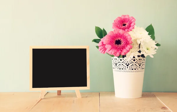 Summer bouquet of flowers on the wooden table and blackboard with room for text with mint background. vintage filtered image — Stock Photo, Image