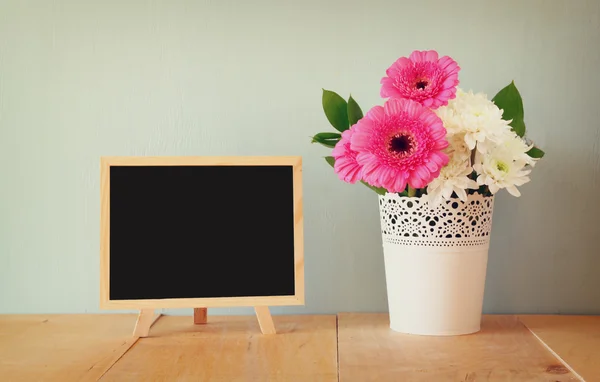 Summer bouquet of flowers on the wooden table and blackboard with room for text with mint background. vintage filtered image — Stock Photo, Image