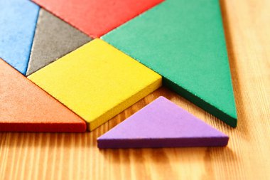 Ahşap masa üzerinde bir kare tangram bulmacanın kayıp bir parça.
