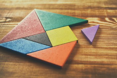 Ahşap masa üzerinde bir kare tangram bulmacanın kayıp bir parça.