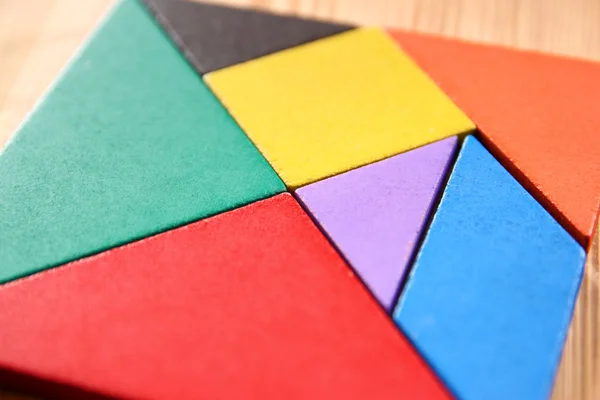 En saknad bit i en fyrkantig tangram pussel, över träbord. — Stockfoto