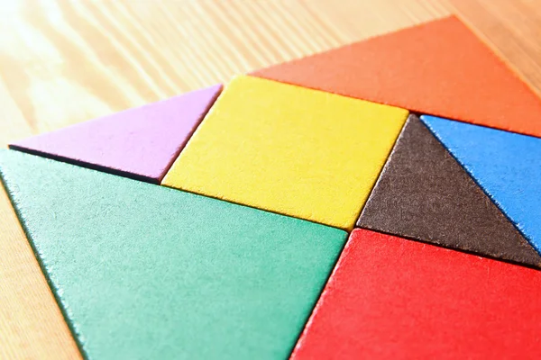 Chybějící kousek do čtvercové tangram puzzle, dřevěný stůl. — Stock fotografie