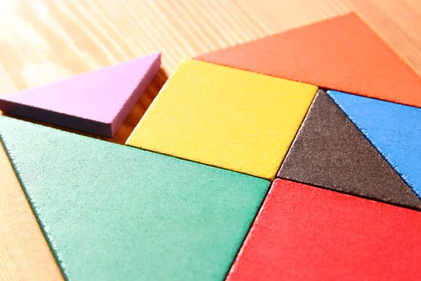 A hiányzó darabot, egy négyzet alakú tangram puzzle, fából készült asztal fölé. — Stock Fotó