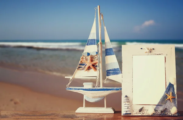 Marco náutico vintage con estrella de mar sobre mesa de madera y fondo de playa de mar. imagen filtrada retro —  Fotos de Stock