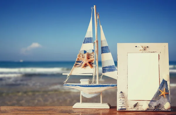 Marco náutico vintage con estrella de mar sobre mesa de madera y fondo de playa de mar. imagen filtrada retro —  Fotos de Stock