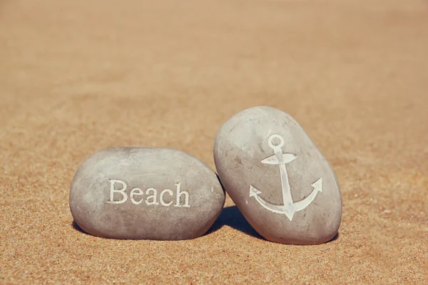 Two stone pebbles with the word beach and anchor sign over sandy beach — Stock Photo, Image