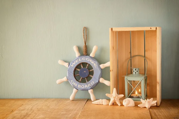 Old nautical wood wheel, lantern and shells on wooden table over wooden aqua background — Stock Photo, Image