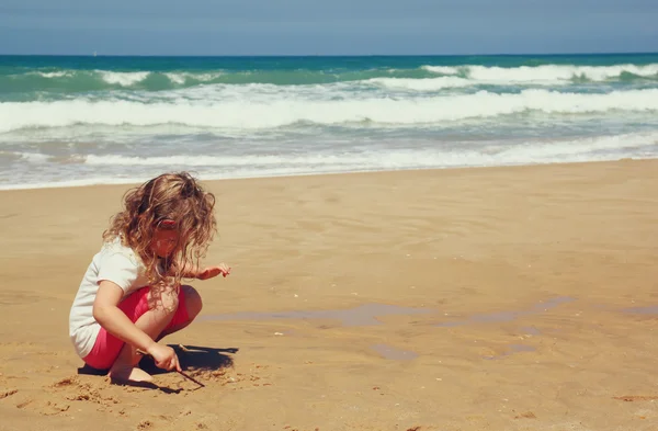 Cute happy kid (girl) playing at the beach — Stock Photo, Image