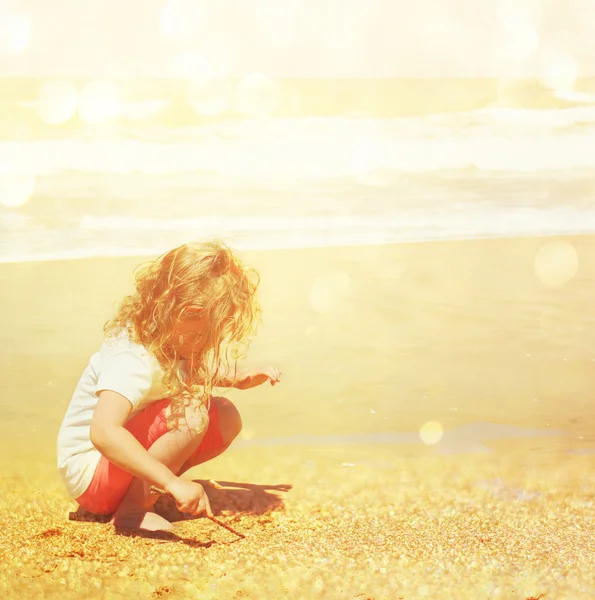 प्यारा खुश बच्चा (लड़की) समुद्र तट पर खेल रहा है। चमकदार ओवरले के साथ टोन छवि — स्टॉक फ़ोटो, इमेज