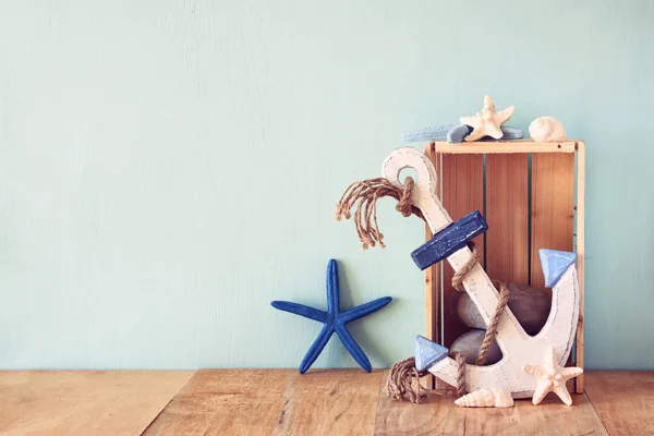 Old nautical wood anchor and shells on wooden table over wooden aqua background — Stock Photo, Image