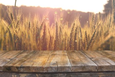 Wood board table in front of field of wheat on sunset light. Ready for product display montages clipart