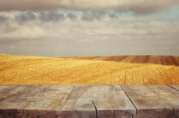 Mesa de tábua de madeira em frente ao campo de trigo ao pôr do sol. Pronto para montagens de exibição de produtos — Fotografia de Stock