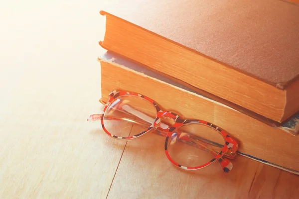 Old books with vintage glasses on a wooden table. retro filtered image — Stock Photo, Image