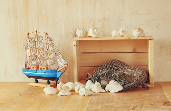 Caixote de madeira velha, barco e conchas naturais na mesa de madeira — Fotografia de Stock