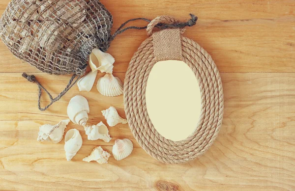 Top view of vintage nautical frame from ropes and natural seashells on wooden table — Stock Photo, Image