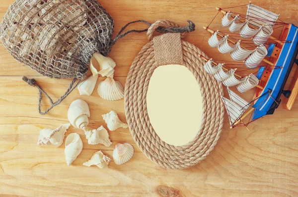 Pohled shora vinobraní námořních rámu z lana, dřevěný člun a přírodní mušle na dřevěný stůl — Stock fotografie