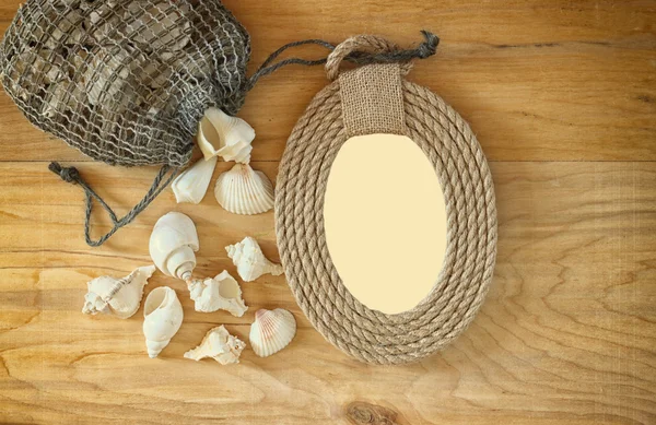 Top view of vintage nautical frame from ropes and natural seashells on wooden table — Stock Photo, Image