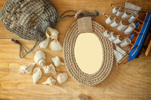 Top view of vintage nautical frame from ropes, wooden boat and natural seashells on wooden table — Stock Photo, Image