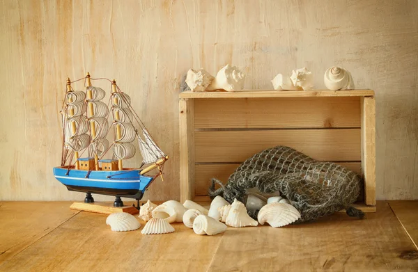 Vecchia cassa di legno, barca e conchiglie naturali sul tavolo di legno — Foto Stock