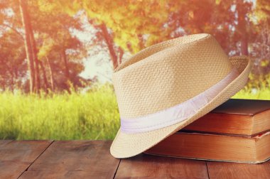 Fedora şapka ve ahşap masa ve akşam doğa ülke yan arka plan üzerinde kitap yığını. gevşeme ya da tatil kavramı
