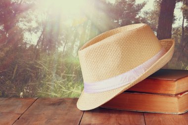 Fedora şapka ve ahşap masa ve akşam doğa ülke yan arka plan üzerinde kitap yığını. gevşeme ya da tatil kavramı