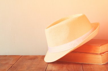 Fedora şapka ve ahşap masa üzerinde kitap yığını. Filtre uygulanmış görüntü