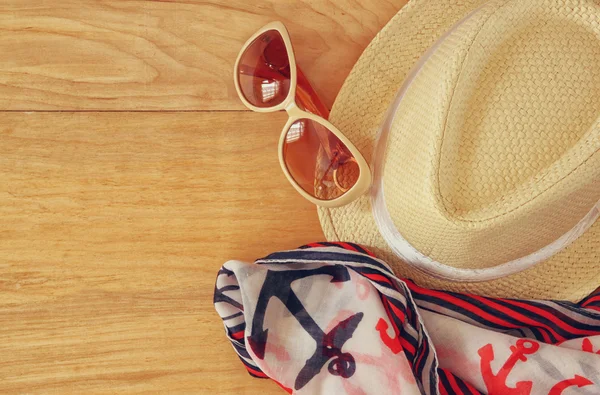 Вид зверху на стильний капелюх жінки сонцезахисні окуляри і планшетний модний морський шарф над дерев'яним столом. концепція відпустки та подорожей — стокове фото