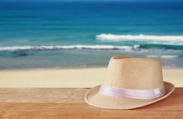 Sombrero Fedora y pila de libros sobre tabla de madera y fondo de paisaje marino. concepto de relajación o vacaciones — Foto de Stock