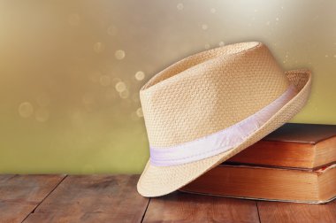 Fedora şapka ve ahşap masa üzerinde kitap yığını