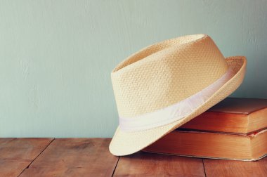 Fedora şapka ve ahşap masa üzerinde kitap yığını