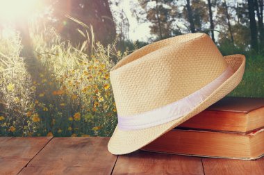 Fedora şapka ve ahşap masa ve akşam doğa ülke yan arka plan üzerinde kitap yığını. gevşeme ya da tatil kavramı