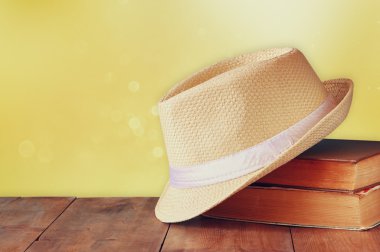 Fedora şapka ve ahşap masa üzerinde kitap yığını