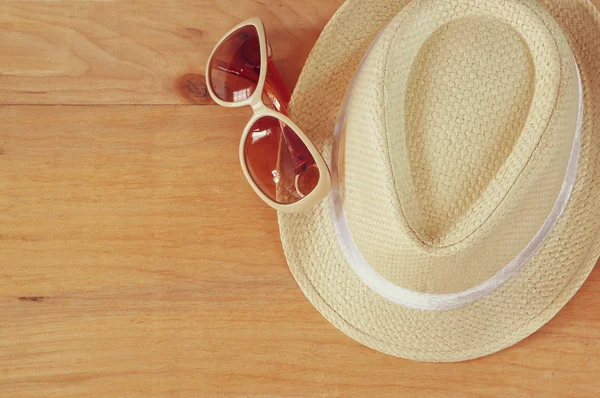 Κάτοψη του fedora καπέλο και γυαλιά ηλίου πάνω από το ξύλινο τραπέζι. έννοια της χαλάρωσης ή διακοπές — Φωτογραφία Αρχείου
