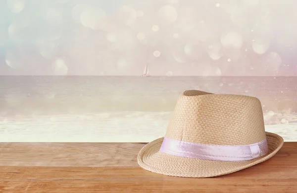 Fedora hat over wooden table and glitter background — Stock Photo, Image